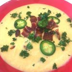 A bowl of soup with bacon and jalapenos.