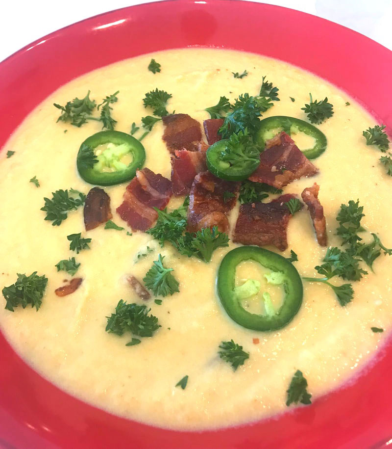A bowl of soup with bacon and jalapenos.